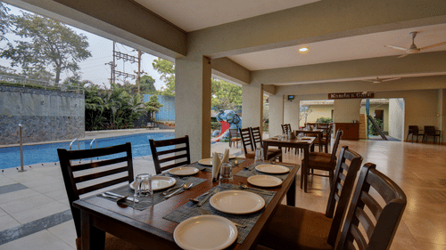 Indoor dining area with neatly arranged tables and poolside view at VITS Lonavala.