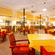 The Courtyard Restaurant at Featherlite Evoma Hotel with red and wooden chairs, dining tables and a wide open seating area nearby.
