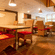 The Courtyard Restaurant at Featherlite Evoma Hotel with wooden dining tables, red cushioned chairs and warm pendant lighting overhead.