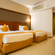 Twin bed room at Featherlite Evoma Hotel with beds dressed in white and gold linen and light wooden flooring throughout the whole room.