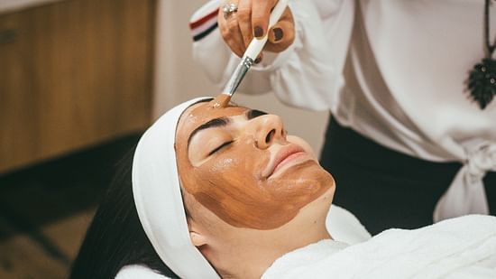 A rejuvenating facial mask being applied by a spa therapist 