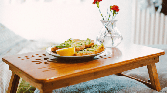 A small table set with a plated meal and a flower vase.