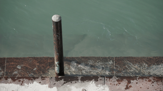 A close-up view of a metal post on a stone ledge overlooking a calm body of water at Ananta Express, Katra.