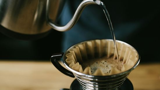 Filter coffee being poured into a paper-lined dripper.