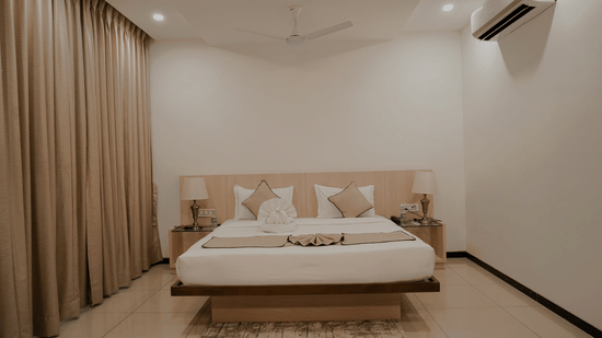 A simple hotel room at Arawali Ananta Elite, Jaipur with a large bed, featuring a large window with curtains.