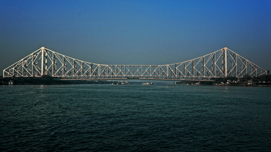 Howrah Bridge spanning the Hooghly River under a clear blue sky in Kolkata.
