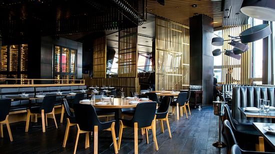 A restaurant with furniture and tables arranged and prepared for guests.