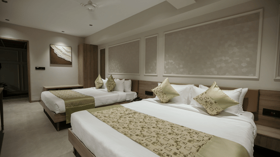 Spacious twin bedroom at Biznotel by Pride Surat featuring two large beds, elegant wall moldings, and neutral decor.