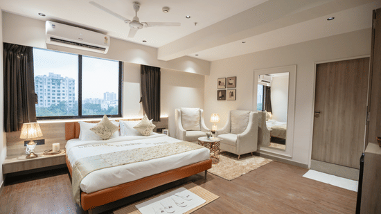Spacious and modern hotel room at Biznotel by Pride Surat featuring a comfortable bed, large windows, and a seating area.