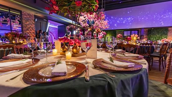 A large, ornate dinner table with colourful floral arrangements and candles, set in a beautifully decorated room