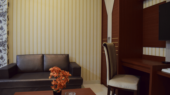 A cozy and well-furnished hotel room with sofa seating, study desk, and elegant decor, ideal for those looking for the best place to stay in Varanasi with family.