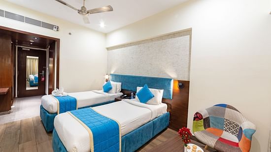 A corner close-up view of the superior room at Icon Boutique Hotel by Bhagini, Domlur. The room includes a twin-sized bed, a ceiling fan, and a sofa for relaxation, offering a cozy and comfortable atmosphere with modern furnishings.