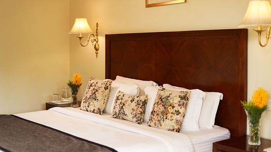 Closer view of a beautifully tucked bed with soft lines and pillows along with bedside lamps - Lamrin Norwood Green, Palampur