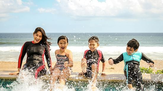 Image of a women and few kids playing in water and beach in the background