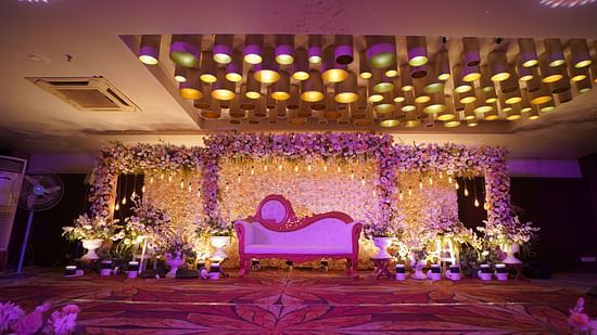 Luxurious wedding stage setup with ornate pink and golden decorations and floral arrangements at Voyage Milestone Hotel and Banquet Siliguri