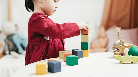 A kid playing with wooden toys in a playroom