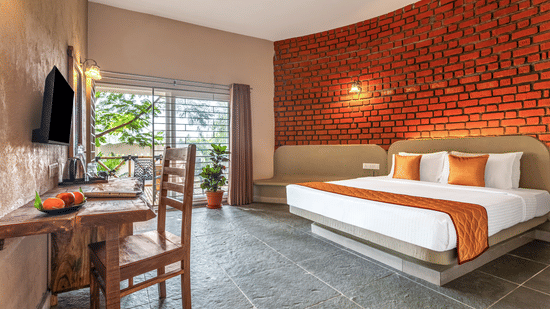 View of a suite interior showing the seating area and sliding doors to the balcony - Nature Trails Ashoka Resort Hampi