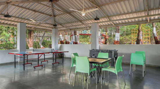 Covered seating area with green chairs and tables on a concrete floor at Nature Trails Durshet.