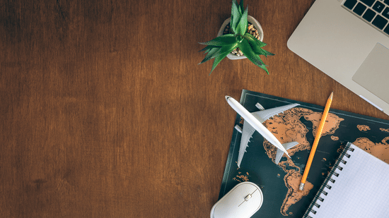 airplane-miniature-notepad-world-map-laptop-wooden-table