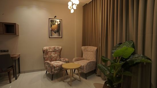 Suite Room living area with sofa chairs and a chandelier - Pride Comfort, Dwarka