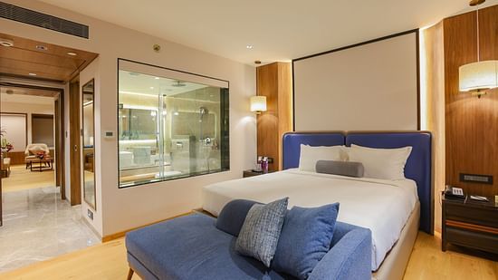 A hotel room with a bed, a couch, and a view of the outside - Pride Hotel Pune