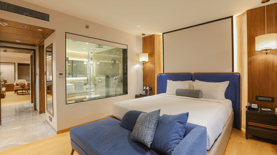 A hotel room with a bed, a couch, and a view of the outside - Pride Premier Pune