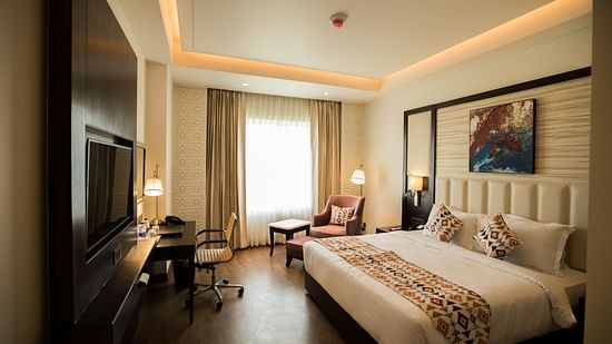 suite room at Ramada by Wyndham Kapurthala featuring a bed, work desk and a television 2