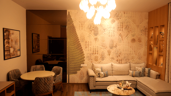 Lounge-style seating at Sarovar Portico, Somnath with sofas, chairs, tables, and patterned wall decor.