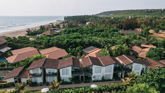 an aerial vie image of the facade of sibaya beach resort, morjim beach that is surrounded by lush tropical greenery
