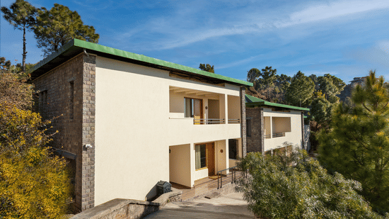 Facade of a 2-storey building in the premises of Suryavilas Luxury Resort and Spa on a sunny day amidst trees