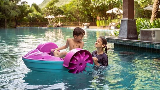 two kids on a pedalled boat in the swimming pool - The Ananta Udaipur