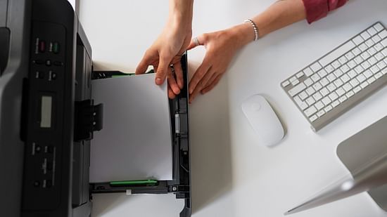 Top view of an employee using a printer in an office setting, representing the concept of fax services.