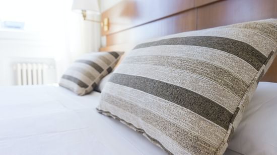 a tidy bed with white sheets and two pillows with a headboard after room service