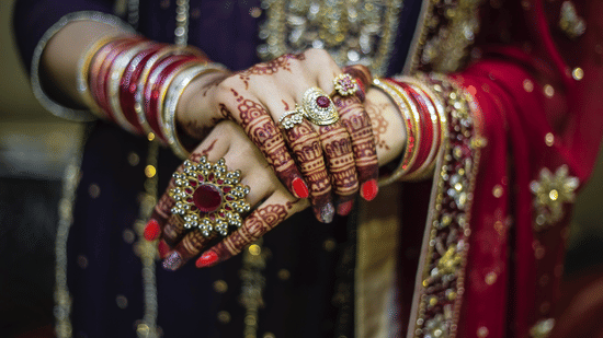 A close-up of bridal mehendi on hands with gold jewellery.