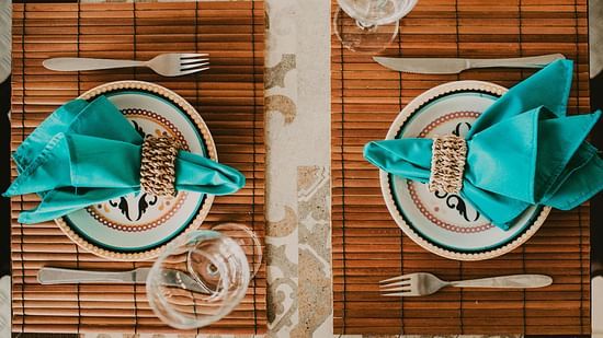 An image of a table laid out with two plates, two glasses, napkins, and cutlery