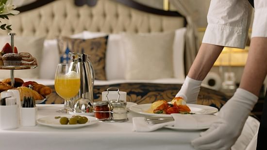 A waiter arranging an in-room dining set-up