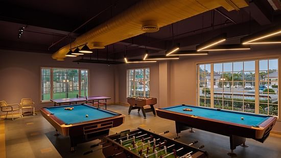 Indoor game room featuring two pool tables and a foosball table, with large windows allowing natural light to illuminate the stylish space - Voyage The Solitaire Bliss.