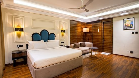 Full view of the luxury room with a king-sized bed and a sofa in the corner at Wedlock Greens Hotel & Resort, Dhanbad