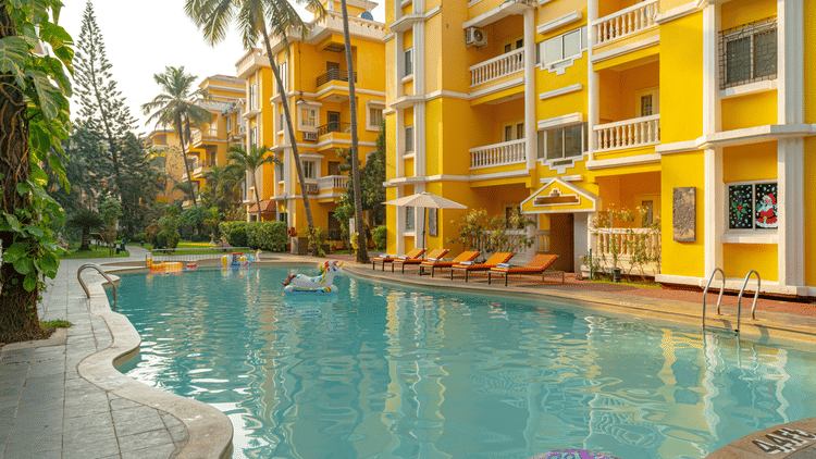 An image of an outdoor swimming pool framed by yellow buildings.