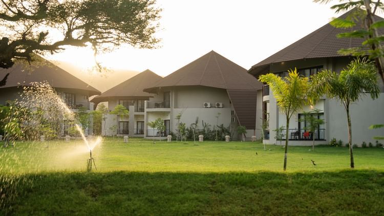 Lush green lawn with water sprinklers and scenic villas in the background at Ananta Spa and Resort, Ajabgarh.