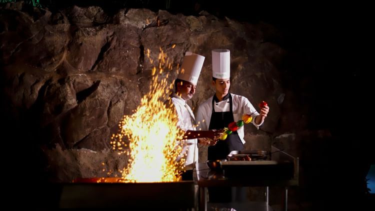 Chefs cooking food near a fire pit