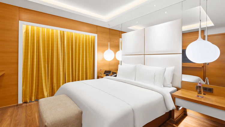 Club Suite room with a cozy high bed and stylish hanging bedside lamps at The Residency Towers Coimbatore