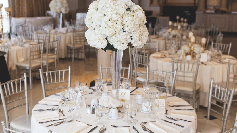 Banquet hall set up for an event, featuring round tables with white tablecloths and silverware.