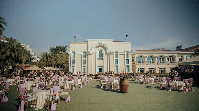 Wide view of a landscaped hotel lawn arranged with event seating against a classic modern building facade.