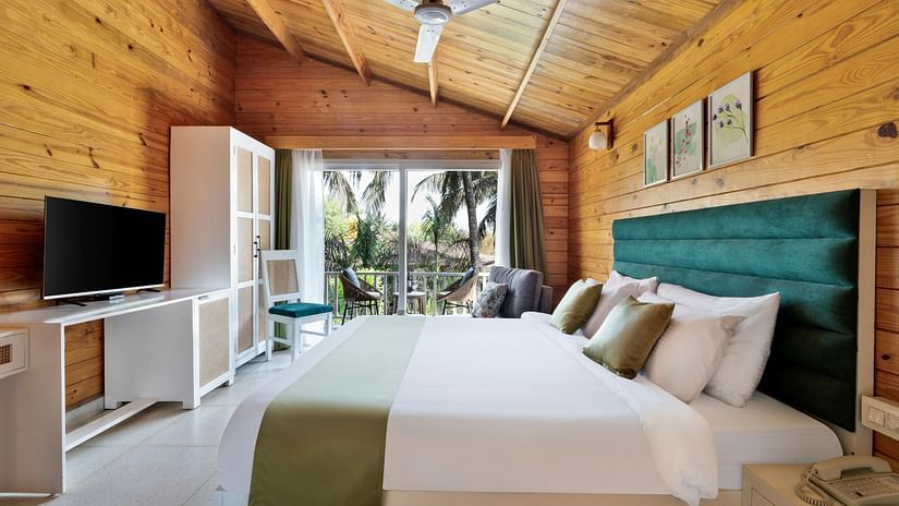 A view of the standard room at Aralea Beach Resort by Stone Wood, Morjim with a queen bed, TV  and view through the balcony 