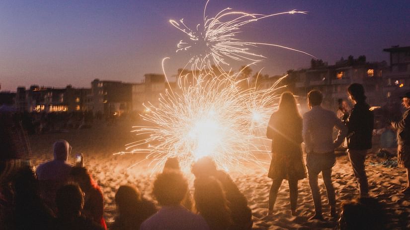 a group of people celebrating on a beach with crackers in the night