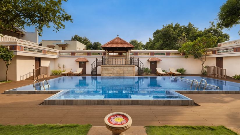 A view from the lawn of the Swimming pool at Chidambara Vilas with trees and blue sky in the view.