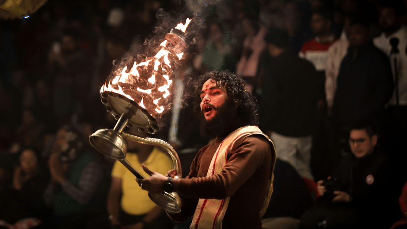A man performs a ritual with flaming lamps at night