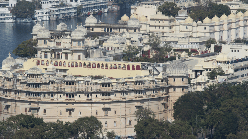 A far out view of the City Palace with other buildings and trees in view.
