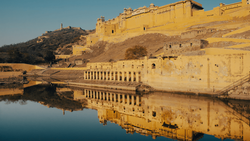 A wide shot rof Amer Fort eflected in the waters of Maota Lake.